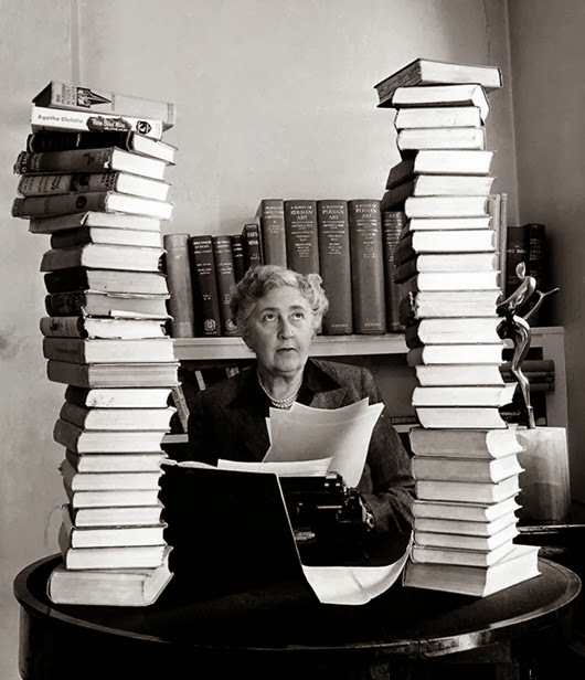 Volume 2, Page 114, Picture, 21. Literature Mystery author and writer, Agatha Christie, pictured at her home, Winter-Brook House, sitting behind her desk with books piled high.