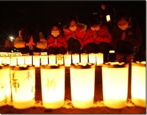 Girls pray after arranging candles at a candlelight event in Iwaki, Fukushima prefecture March 10, 2012. REUTERS/Kim Kyung-Hoon