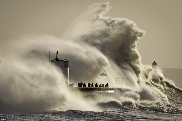 People photograph enormous waves as they break on Porthcawl, South Wales, where very strong winds and high seas from Winter Storm Hercules create dangerous conditions on 6 January 2014. Thrill-seekers were still risking their lives to storm-watch, defying guidance from police and the Environment Agency to stay away from dangerous coastlines. Photo: PA / Daily Mail