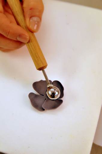 Next, she rolls out the petals using this metal tool.
