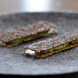 Mini sandwiches. Entre la base de peau de poulet grillée et le dessus de pain de seigle, un mélange de fromage fumé et de livèche.