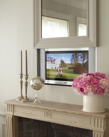 A television is over the living room mantel; an antiqued mirror lifts to reveal it.