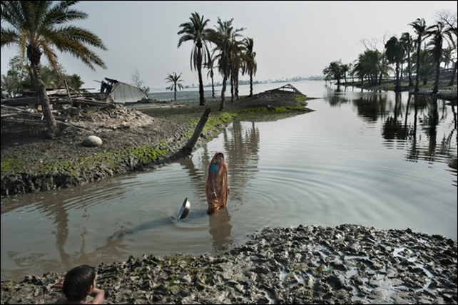 A woman stood where her house was before Cyclone Aila destroyed it in 2009. Scientists expect rising sea levels to submerge 17 percent of Bangladesh's land and displace 18 million people in the next 40 years. Photo: Kadir van Lohuizen / The New York Times