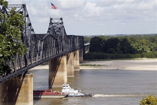 A towboat and its barges pass under the old Mississippi River bridge at Vicksburg, Miss., Thursday, 26 July 2012. In a switch of extremes, the river has dropped to very low levels this summer unlike last year when the river was flooding much of the Delta due to record high levels. The drop in water level now exposes the river bottom, forcing river traffic to a trickle as barges are forced to lessen their loads to keep from getting stuck on sandbars. Rogelio V. Solis / AP Photo
