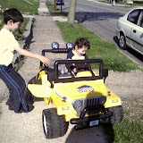 Kai and Eidan riding on the neigbor's battery powered mini Jeep