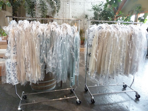 No, these are not the bridesmaids' dresses. The racks are filled with linens from La Tavola. Since the floorplan was set out in a confetti pattern, there were multiple table sizes, and three different linen options to add dimension.