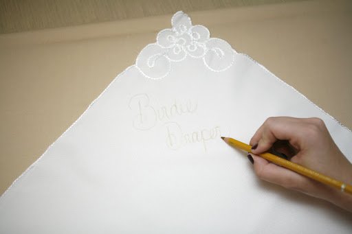 Step 1: With the pencil, trace out the guest's name and table number. It'll serve as your stitching guide. Step 1: With the pencil, trace out the guest's name and table number. It'll serve as your stitching guide.