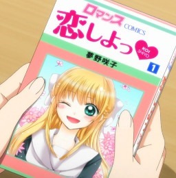 Someone holding a copy of Nozaki's manga, Koi Shiyou, with the main character Mamiko smiling on the cover