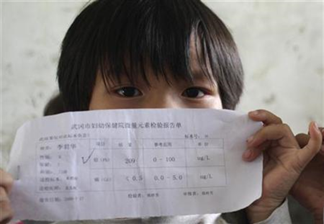 A child holds a laboratory sheet showing high levels of lead in her blood at a village in Wugang, Hunan province August 18, 2009. Reuters / China Daily