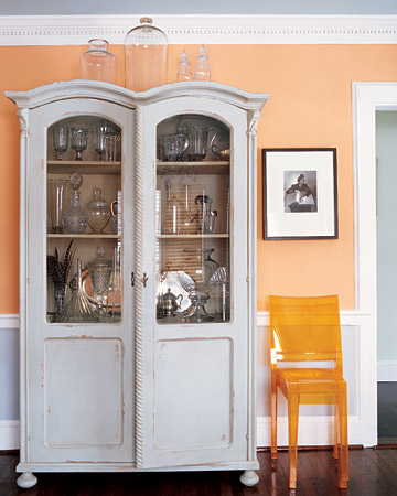 In this living room, Philippe Starck chairs sit next to a weathered celadon cabinet. The pale-orange walls unite this unexpected pair.