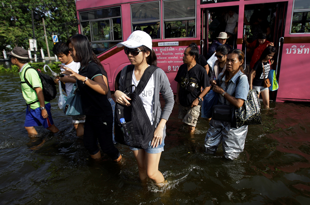 Thai residents depart a bus on a flooded street in Bangkok on Friday, 4 November 2011. Aaron Favila / Associated Press