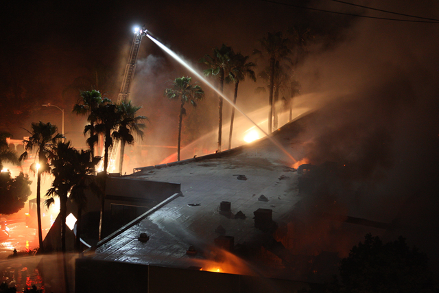 Firefighters spray water on a building set aflame by a wildfire on 14 May 2014, in Carlsbad, California. Photo: U.S. News & World Report