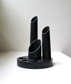 Dark gray plastic desk organizer with 3 cylinders and 3 circular compartments on the base