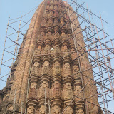 These tiers are clearly articulated, lending an almost rounded quality to the towered profile. Large arched niches are positioned at the base of the central bands.