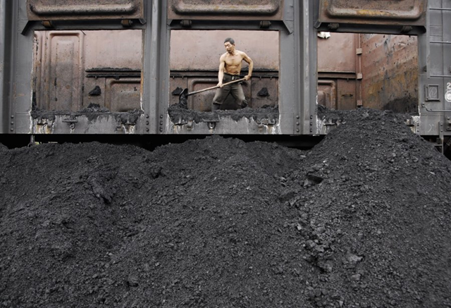 A worker unloads coal at a coal dump site of a railway station in Xiangfan, central China's Hubei province, 8 October 2007. Photo: REUTERS/Stringer