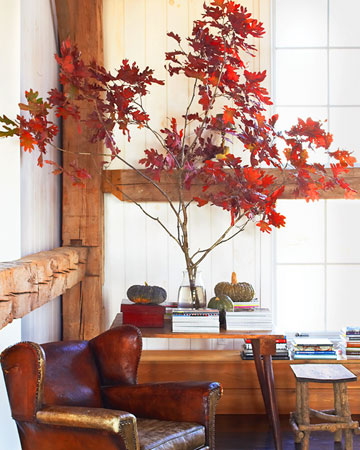 Fall: One temporary way to bring autumn indoors is to create a natural display, such as a blazing tree branch and greenish gourds.