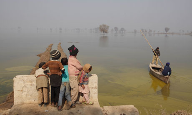 Pakistani children wait by floodwaters for a boat. Pakistan's floods in 2010 affected more than 20 million people. Photograph: Andy Hall for the Guardian
