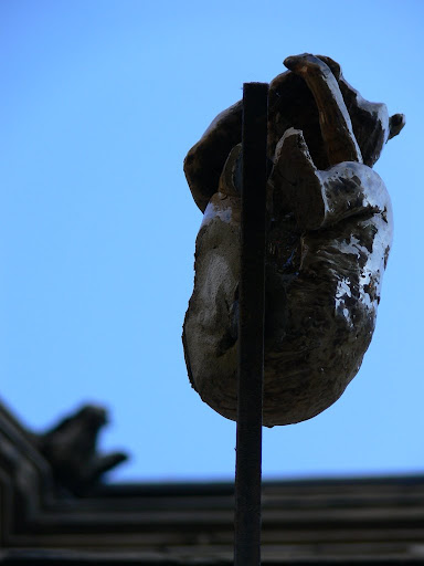 A sculpture of a monkey in metal, as viewed from below.