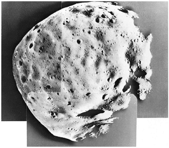 View of Phobos taken by Viking Orbiter 1 from a distance of 480 kilometers (300 miles). This mosaic of 3 pictures was made in February 1977. As seen here, Phobos is about 75% illuminated and is about 21 kilometers (13 miles) across and 19 kilometers (11.8 miles) from top to bottom. North is at top. The south pole is within the large crater (Hall) with a diameter of 5 kilometers (3.1 miles) and will be noted at bottom center where the pictures overlap. Some features as small 20 meters (65 feet) across can be seen. Remarkable features include striations, crater chains, a linear ridge, and small positive features which appear to be resting on the surface. A long linear ridge is seen starting near the south pole and extending to the upper right. A very sharp wall at the intersection of two craters (about 1 kilometer; 0.6 mile across) is seen along this ridge at right. A series of craters runs horizontally in the picture which is parallel to the orbit plane of Phobos. These crater chains are commonly associated with secondary cratering by ejecta from larger impacts. A surprising discovery has been made of what apparently resembles hummocks or small positive features. These features, primarily seen near the terminator (right), are about 50 meters (165 feet) in size and may be surface debris from previous impacts. 