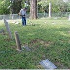 Owen Gleaves weedeats around tombstones