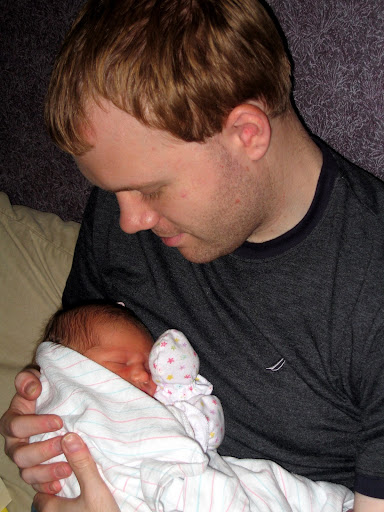 My husband holds our firstborn, hours after her birth