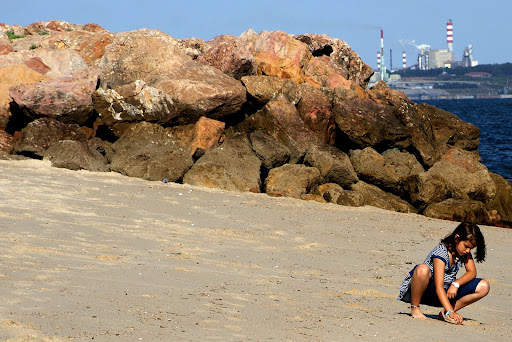 Jovem brinca na areia da praia de Albarquel