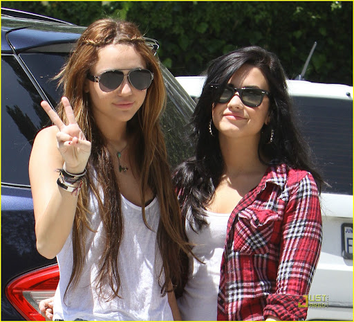 Miley Cyrus, in her short shorts and string tank, out with a friend. They smile for the cameras. April 25, 2010 X17online.com exclusvie