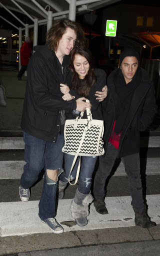 12-15-09 London, UKTeen sensation Miley Cyrus feels the winter chill as she wraps up with a friend to battle the cold weather at Heathrow Airport.EXCLUSIVE PIX by Flynet ©2009818-307-4813 Nicolas