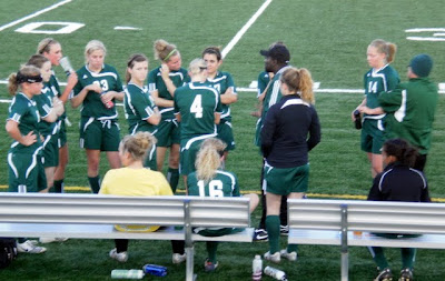 Pella girls soccer coach Sam Mate-Kodjo (black hat) talks with his team in the huddle