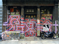 Soho, New York</p>
<p>Graffiti appears in all places and is usually a sign of neglect and dereliction. The area was not derelict, or neglected. The building to either side are newly renovated. I took several shots of this building, setting up a tripod to make sure there was no hand jitter. After the third shot, this couple showed up, the guy basically ordering the girl to sit in the frame so he could take her picture. A very strange situation.</p>
<p>Stuff like this happens all the time. People either do not understand why you are taking a picture, or want to get in on the act.  Too funny.
