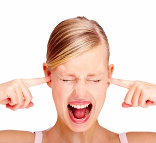 Portrait of disturbed young female screaming while putting finger in her hears