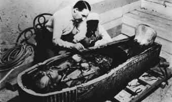 Archaeologist Howard Carter is shown examining King Tut’s sarcophagus.