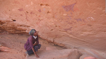 Sada Mire, Somaliland's first archaeologist, crouching next to prehistoric rock art at Dhambalin, a site she discovered in 2007. Somali cave paintings