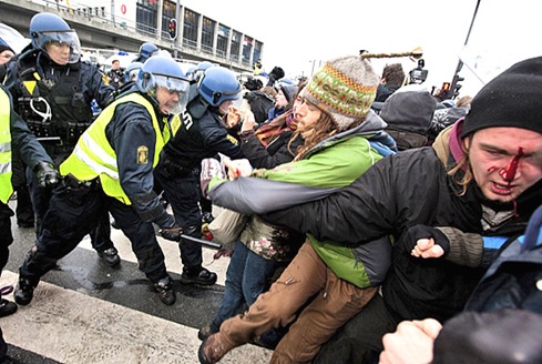 Danish riot police push back protestors, one bleeding, during a demonstration in Copenhagen.