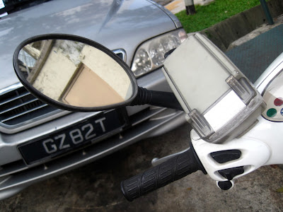 Left-side mirror bent in; one of the perpetrators in the background.
