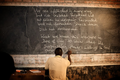 Phanuel Munezero writes 2 Corinthians 4 on chalkboard