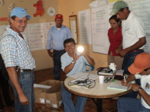 Luis Lanzas, AVODEC dentist holds up a solar lamp, surrounded by AVODEC members.