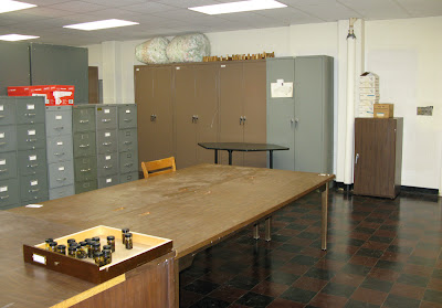 mostly empty room with large table in center and cabinets along the walls