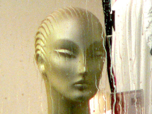 tête de mannequin trés triste derrière sa vitrine par temps de pluie Paris