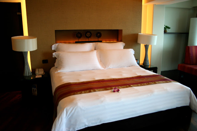 a bed with white sheets and a red and gold striped blanket