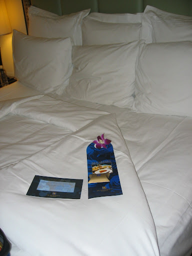 a bed with white pillows and a blue bookmark on it