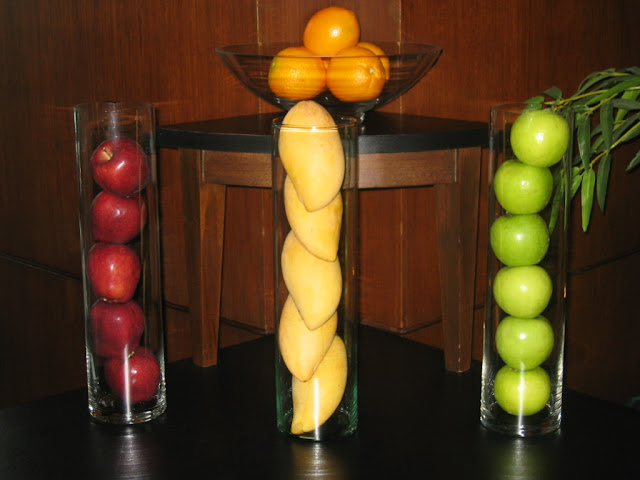 a group of glass vases filled with fruit