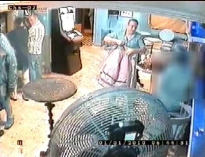 A still from CCTV footage of a suspect being sought in connection with a sex attack in Morecambe on New Year's Day. The suspect is shown above the blurred square on the screen (the blur is concealing the victim), putting on his coat
