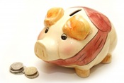 A cute, porcelain piggy bank next to stirling pound coins