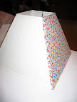 Paint the diluted glue on the shade and stick the fabric to it, smoothing from the center toward the edges
