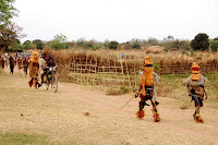 Wild Things Chase Cyclists The kids with the sticks in hand and sacks on their heads are animals. That is, their bodies have become the homes of animal spirits, boogy men of sorts, or so the custom says. These are typical Nyau costumes (pronounced like a cat's meow but with an N). The traditions surrounding the Nyau's costumes and the way they harass kids revolve around a semi-secret society that has roots in traditional shamanistic animism; traditionally those who dress up "become" animals in their own minds and in the minds of community members. Or that's what I'm told. Even though the area is mostly Catholic now, you see somebody dressed up and chasing little kids every few weeks. Recently a new king was anointed in my area (the government calls them Traditional Authorities, in practice they are influential, mainly out of deference to tradition I think), and we saw Nyau all over the place for an entire week. They remind me of the book Where the Wild Things Are.