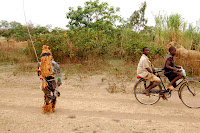 Where the Wild Things Are The kid with the stick and the sack on his head is an animal. That is, his body has become the home of an animal spirit, a boogy man of sorts, or so the custom says. The traditions surrounding the Nyau's costumes and the way they harass kids revolve around a semi-secret society that has roots in traditional shamanistic animism; traditionally those who dress up "become" animals in their own minds and in the minds of community members. Even though the area is mostly Catholic now, you see somebody dressed up and chasing little kids every few weeks. Recently a new king was anointed in my area (the government calls them Traditional Authorities, in practice influential, but mainly out of deference to tradition I think), and we saw Nyau all over the place for an entire week. They remind me of the book Where the Wild Things Are.