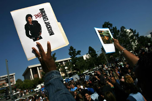 LOS ANGELES - JUNE 25: People hold up Michael Jackson pictures as media and spectators wait for a news conference about Michael Jackson's death at UCLA Medical Plaza June 25, 2009 in Los Angeles, California. The iconic pop star, 50, was rushed to the hospital today after going into cardiac arrest, according to reports. (Photo by Ann Johansson/Getty Images)