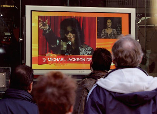 SYDNEY, AUSTRALIA - JUNE 26: Pedestrians stop to watch a television screen announcing the death of pop icon Michael Jackson at the Channel Seven Studio's in Martin's Place on June 26, 2009 in Sydney, Australia. The 50-year old child star was reportedly found not breathing at his LA home and was rushed to UCLA Medical Centre hospital, where he was later pronounced dead apparently from a heart attack. (Photo by Sergio Dionisio/Getty Images)