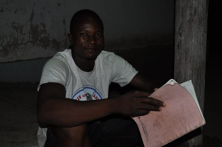 A young man studying by streetlight on the steps of a church.